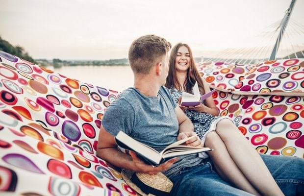 young hipster couple reading books in a hammock at the beach at