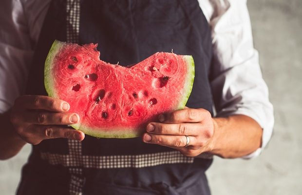 a man in a holding a big piece, striped watermelon. ripe delicious berry. vintage agricultural.