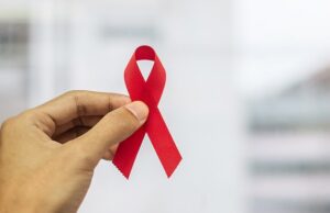 december world aids day awareness month, man holding red ribbon