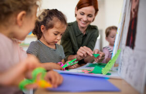 group of small nursery school children with teacher indoors in classroom, art and craft concept.
