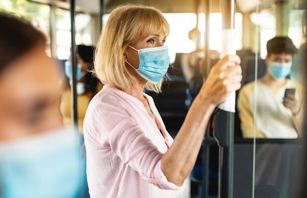 focused mature woman wearing medical mask taking bus