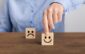 hand of a businessman chooses a smiley face on wood block cube