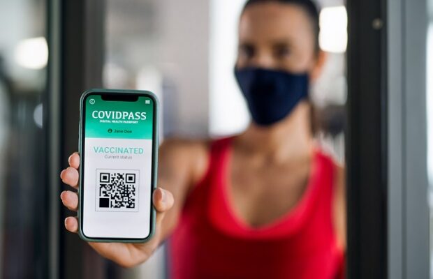 woman with vaccination certificate app on smartphone in gym, coronavirus concept.