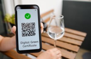 woman demonstrates digital green certificate with qr code in mobile phone sitting in the cafe.
