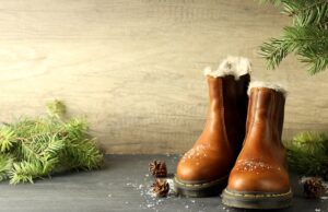 concept of winter clothes with boots on dark wooden table