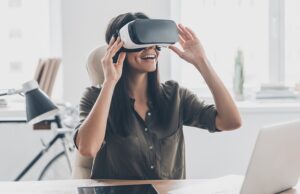 future is right now. confident young woman adjusting her virtual reality headset and smiling while sitting at her working place in office