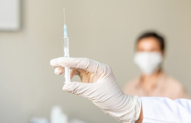 anonymous healthcare worker vaccinating middle aged female patient. blurred background