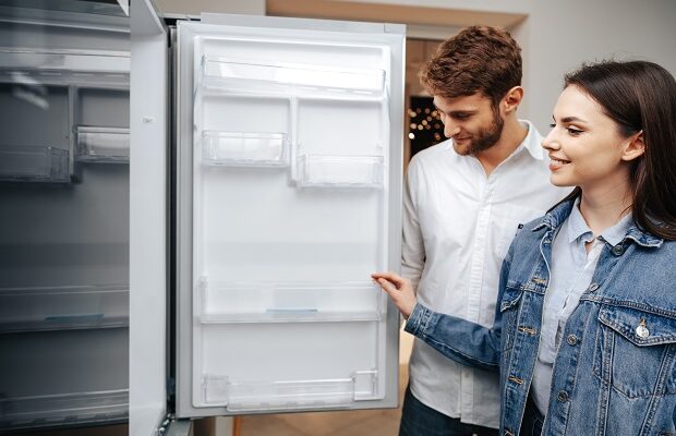 young couple selecting new refrigerator in household appliance store
