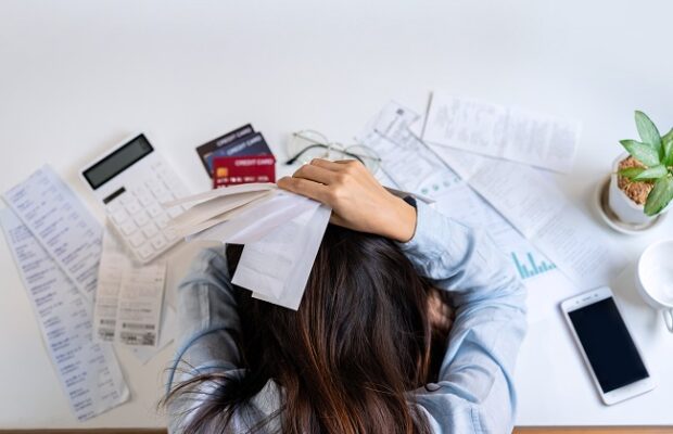 stressed young woman calculating monthly home expenses, taxes, bank account balance and credit card bills payment, income is not enough for expenses