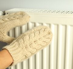 female hands in mittens keep hands near radiator