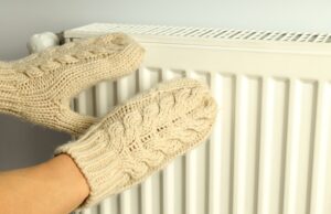 female hands in mittens keep hands near radiator