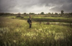 hunting,hunter,men,with,gun,standing,in,field,nearby,river