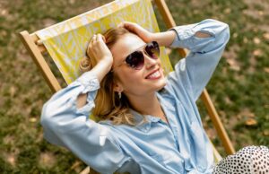 stylish blond woman sitting in city park summer fashion