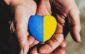 senior man or soldier hands holding heart shape stone painted with ukraine flag