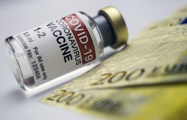 covid 19 vaccine next to several two hundred euro banknotes, concept image