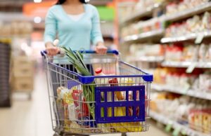 woman with food in shopping cart at supermarket