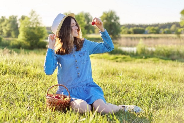 beautiful teenage girl in denim dress hat eating ripe strawberries