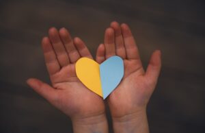 blue and yellow coloured paper cut heart in palms of a child
