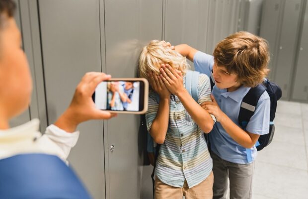 schoolchildren cruel boys filming on the phone torturing bullying their classmate in school hall