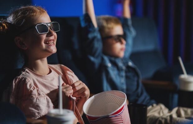 small children with 3d glasses and popcorn in the cinema, watching film.
