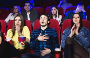 group of people watch a horror movie at the cinema.