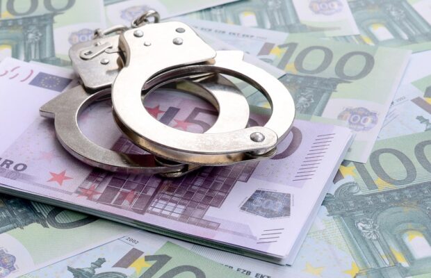 police handcuffs lies on a set of green monetary denominations o