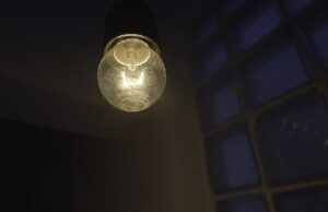 light bulb without lamp hanging from the ceiling in the dark. stock footage. lighting of an old and gloomy with colorful lights on the wall, concept of party.