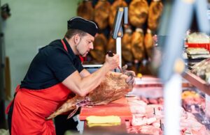 butcher boning a ham in a modern butcher shop