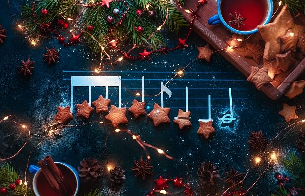 christmas melody notes flat lay with star shaped cookies, fir tree branches, wooden tray, anise stars, and decorations. christmas carol concept for a header or postcard