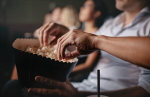 young people eating popcorn in movie theater