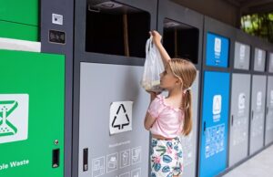 little caucasian girl seven years old throwing waste into recycle bin.