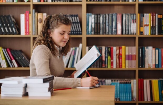girl studying among books sitting at the desk among books