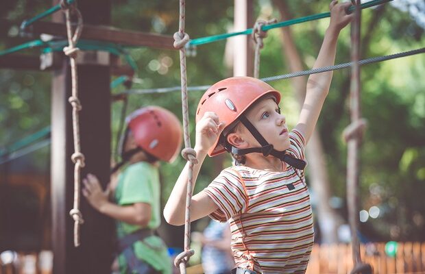 little boy make climbing in the adventure park.