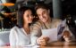 happy man and woman looking at menu in restaurant