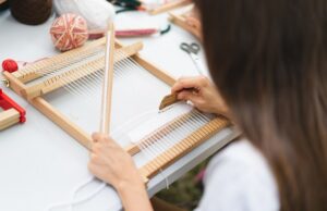 girl weaving small rug with pattern at masterclass on weaving.