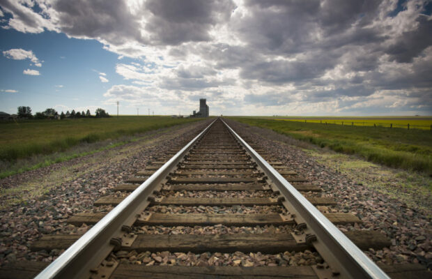 railroad tracks recede to the horizon, dark summer sky approaching
