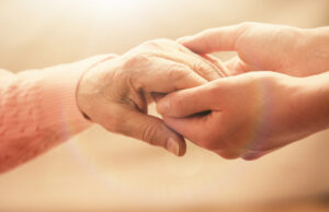 old,and,young,holding,hands,on,light,background,,closeup