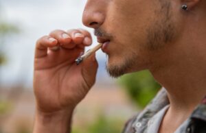 close up portrait of a man who smokes a joint of marijuana.