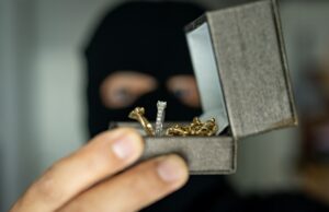 masked man holding a gift box with jewelry. the concept of theft.