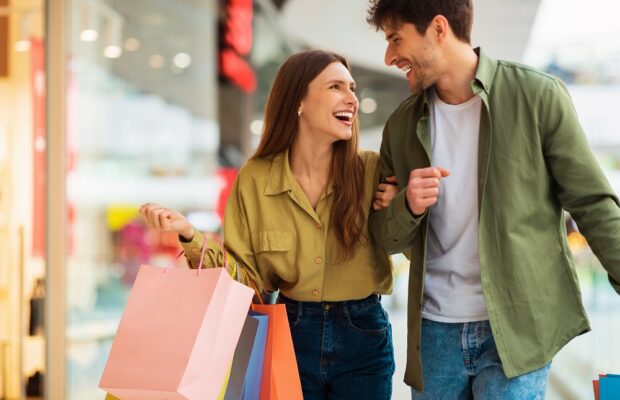 joyful couple carrying shopping bags laughing spending time in mall