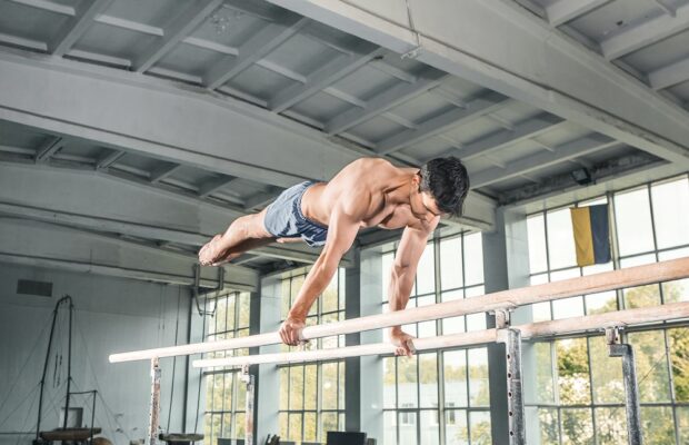 male gymnast performing handstand on parallel bars
