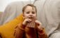 little adorable boy sitting on the couch at home and eating chocolate bar. child and sweets, sugar confectionery. kid enjoy a delicious dessert. preschool child with casual clothing. positive emotion.