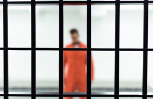 prisoner in prison cell with metallic bars on foreground