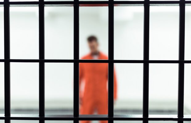 prisoner in prison cell with metallic bars on foreground