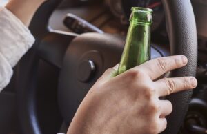 Șofer aflat la volanul mașinii cu sticla de bere în mână. Sub influența alcoolului