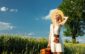 blonde woman with suitcase and camera in wheat field in summer t