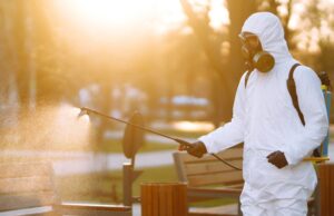 a man wearing special protective disinfection suit sprays sterilizer in the public place. covid 19.