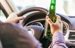 man drinking alcohol while driving the car