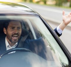 close up photo of an angry young businessman driving a car, shouting and waving his hands